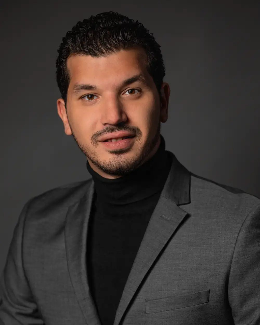 Professional Headshot Example of a man in a gray suit with dark hair.